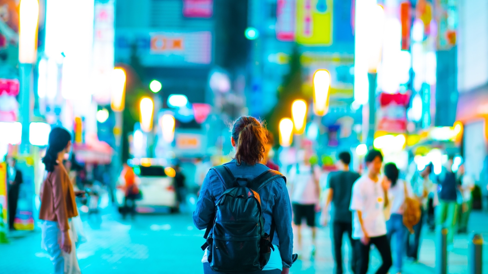 Young woman backpacker walking the street at night in Tokyo, Japan