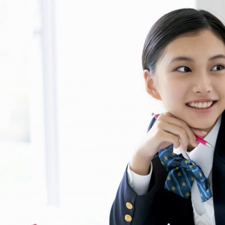 Japanese schoolgirl is smiling at her desk.
