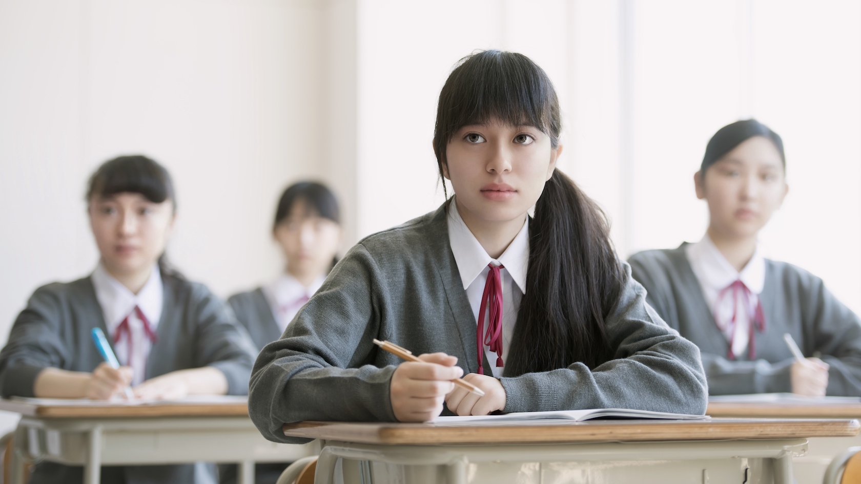 Adobe Stock 269132108. Japanese schoolgirls listening and taking notes in class.